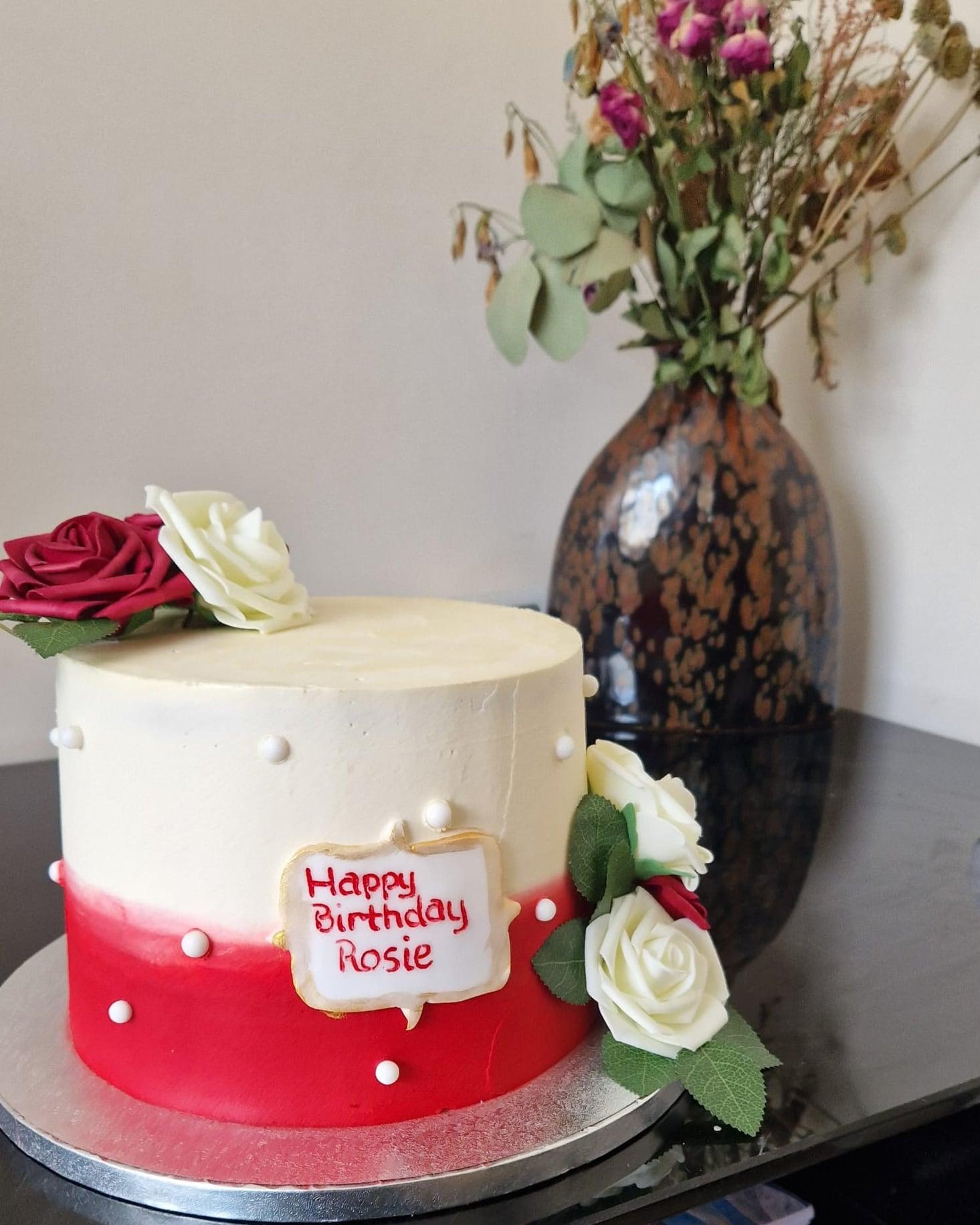 An ivory and ruby birthday cake dressed with fresh roses and piped pearls